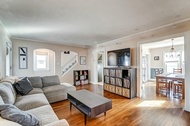 living room with baseboards, hardwood / wood-style floors, stairs, crown molding, and a notable chandelier