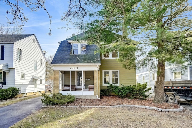 view of front facade with covered porch, aphalt driveway, and roof with shingles