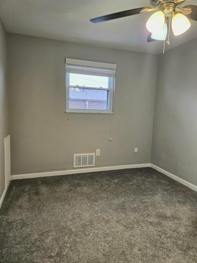 spare room featuring dark colored carpet, a ceiling fan, visible vents, and baseboards