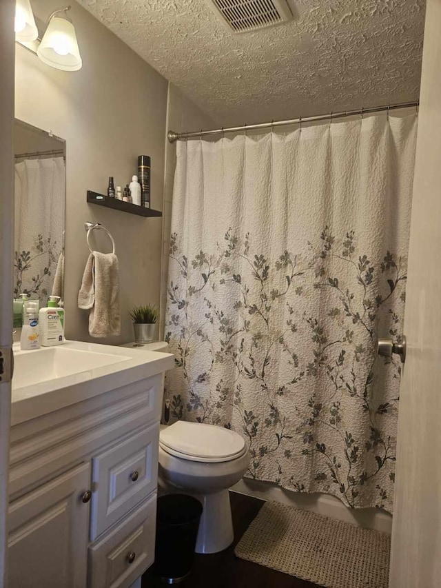 full bathroom with toilet, visible vents, a textured ceiling, and vanity