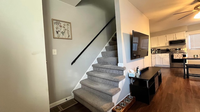 staircase featuring visible vents, baseboards, a ceiling fan, and wood finished floors