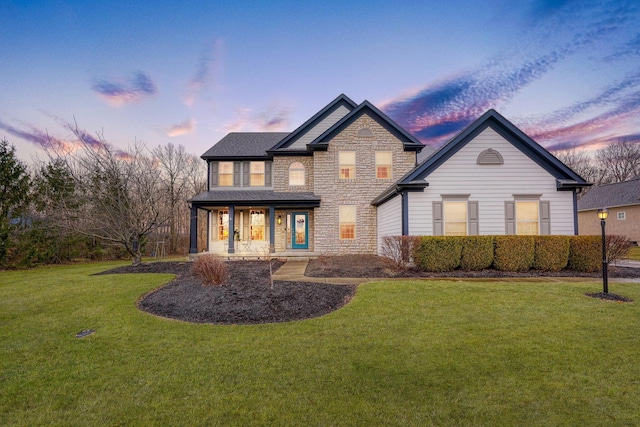 rear view of property with stone siding, a yard, and a porch