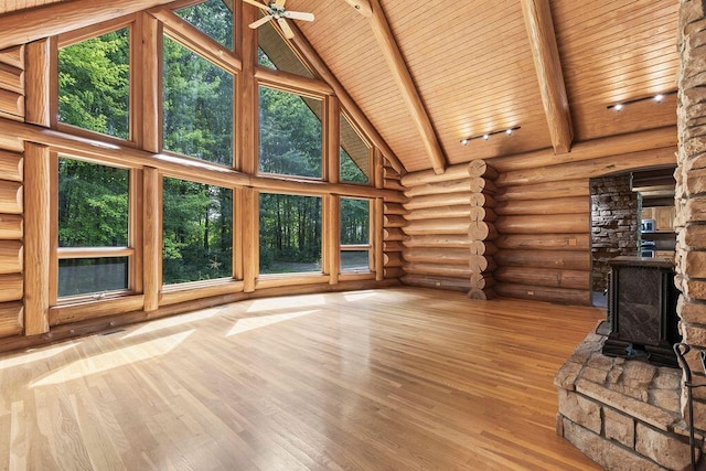 unfurnished living room with wooden ceiling, wood finished floors, beamed ceiling, a wood stove, and high vaulted ceiling