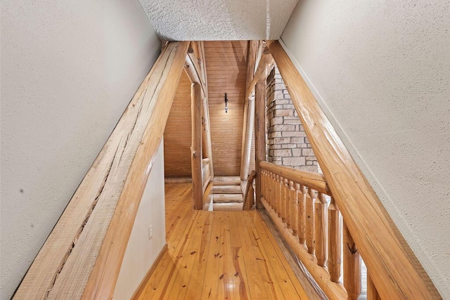 staircase with a textured ceiling, a textured wall, and wood-type flooring