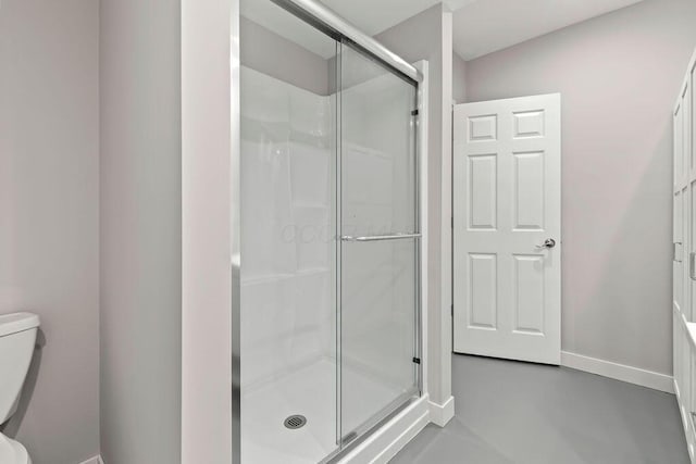 bathroom featuring finished concrete flooring, a shower stall, toilet, and baseboards