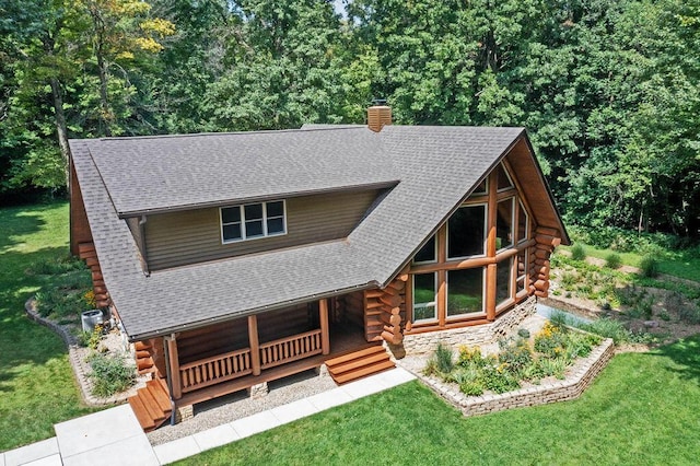 log-style house featuring covered porch, a front yard, log siding, and roof with shingles