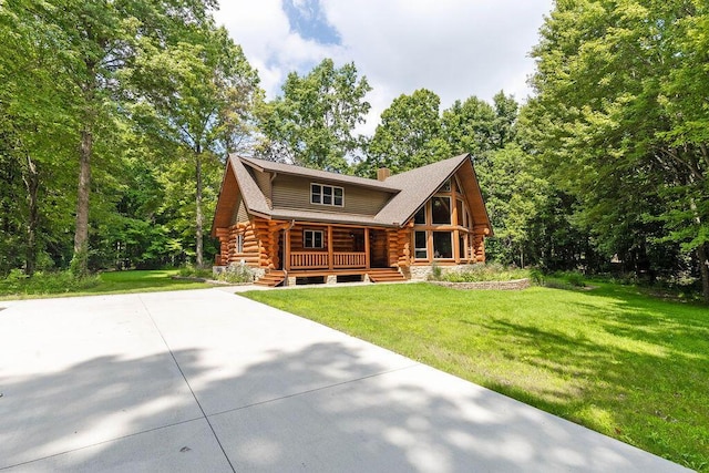 log home featuring a chimney, a porch, a front yard, log exterior, and driveway