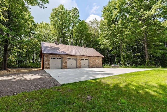 exterior space featuring stone siding, a detached garage, a chimney, metal roof, and a front yard