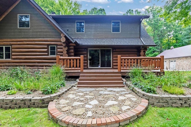 back of property featuring log siding, a deck, and roof with shingles