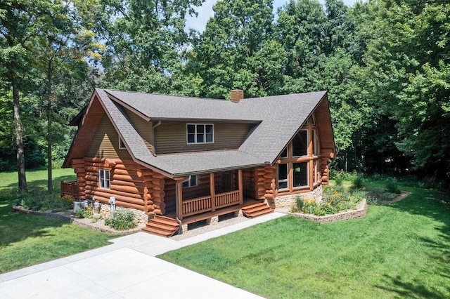 log home with a chimney, log siding, roof with shingles, covered porch, and a front yard