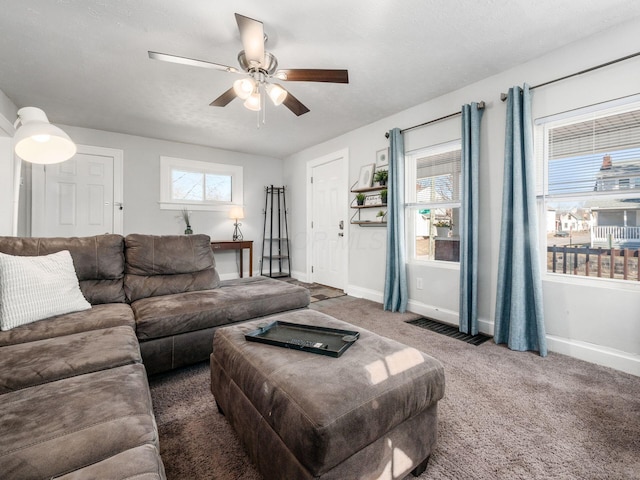 living room featuring visible vents, baseboards, a ceiling fan, and carpet flooring