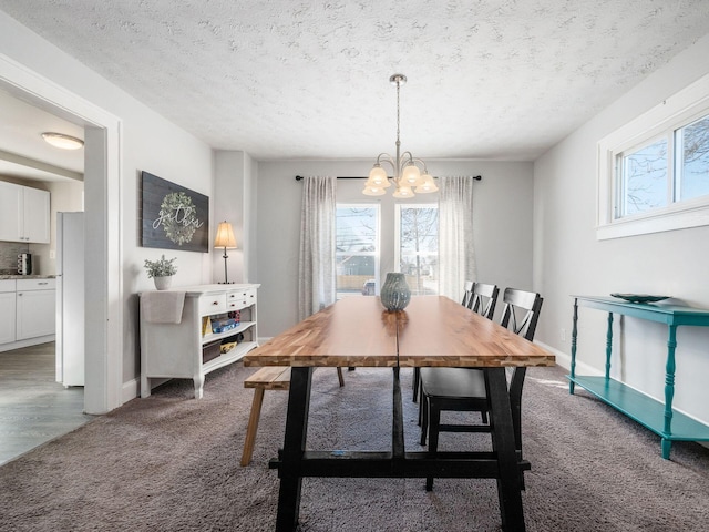 carpeted dining room with baseboards, a notable chandelier, a healthy amount of sunlight, and a textured ceiling