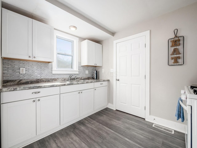 kitchen with visible vents, a sink, tasteful backsplash, white cabinets, and dark wood-style flooring