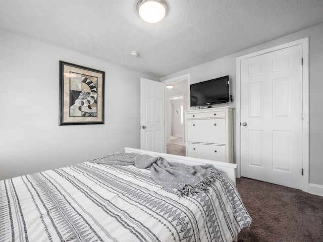 bedroom with dark carpet and a textured ceiling