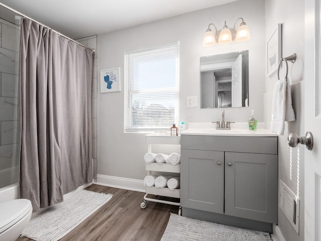 bathroom featuring vanity, wood finished floors, visible vents, baseboards, and toilet