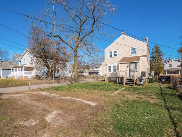 back of property with a lawn, a chimney, and fence