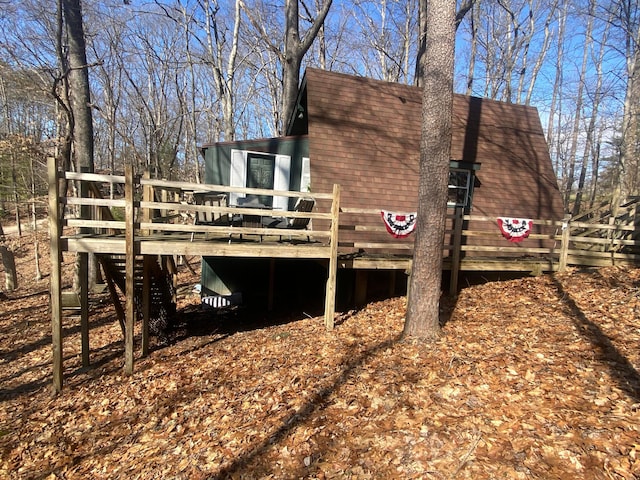 back of property featuring a shingled roof and a wooden deck