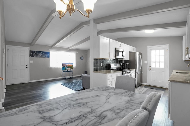 kitchen with lofted ceiling with beams, a sink, white cabinetry, appliances with stainless steel finishes, and tasteful backsplash