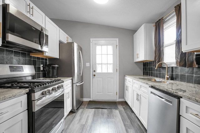 kitchen with a healthy amount of sunlight, appliances with stainless steel finishes, white cabinets, and a sink