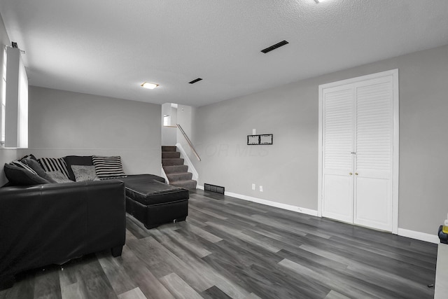 living area featuring stairs, a textured ceiling, wood finished floors, and baseboards