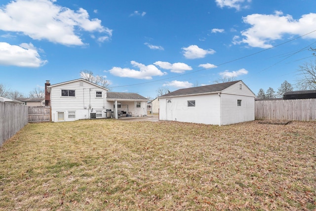 rear view of house with an outbuilding, a fenced backyard, a yard, and a patio
