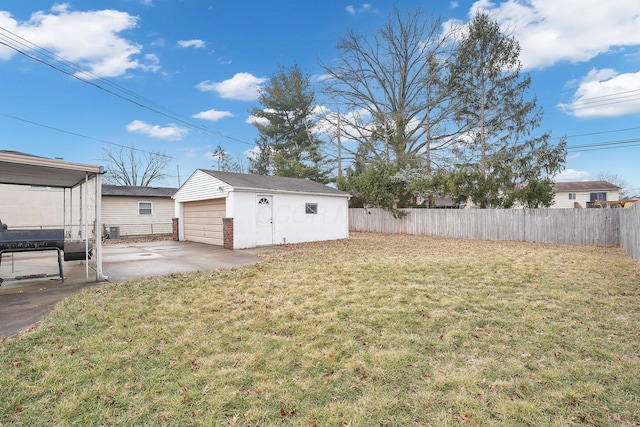 view of yard featuring an outbuilding, a fenced backyard, a garage, driveway, and a patio area