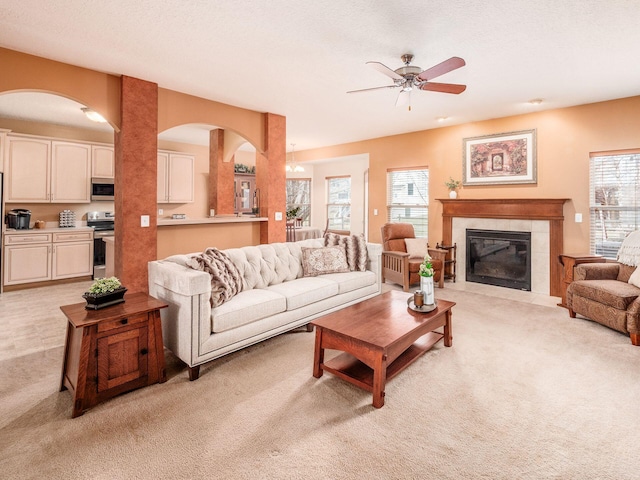 living room with a wealth of natural light, light carpet, ceiling fan, and a tile fireplace