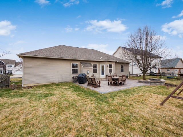 rear view of house with a lawn, fence, a fire pit, and a patio