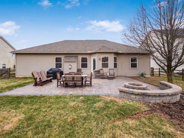 back of house featuring an outdoor fire pit, fence, a yard, roof with shingles, and a patio area