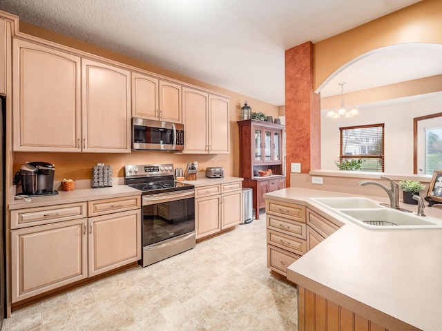 kitchen featuring light brown cabinets, stainless steel appliances, a sink, and light countertops