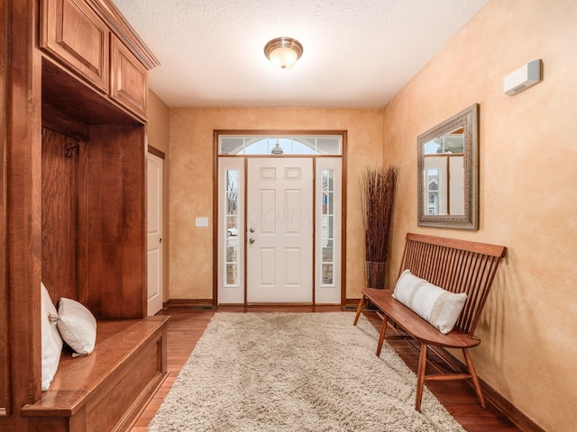 entrance foyer featuring a textured ceiling, baseboards, and wood finished floors