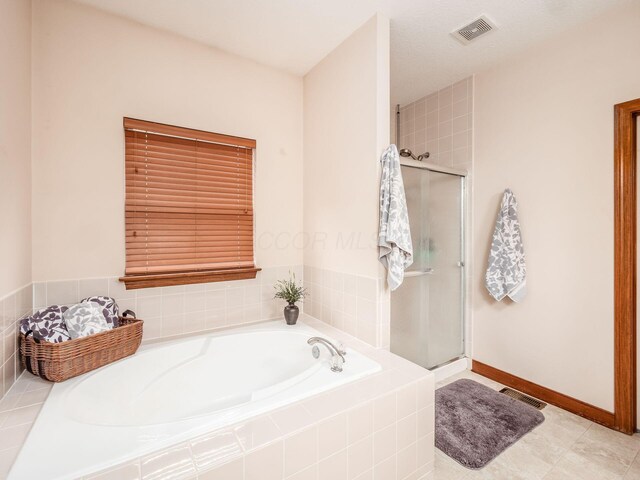 bathroom with a stall shower, visible vents, and a garden tub