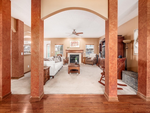 living room featuring a ceiling fan, a tiled fireplace, baseboards, and wood finished floors