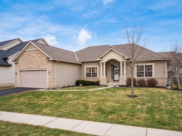 view of front of home with driveway, a garage, stone siding, roof with shingles, and a front lawn