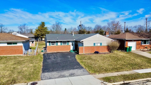 ranch-style house featuring driveway, brick siding, and a front yard