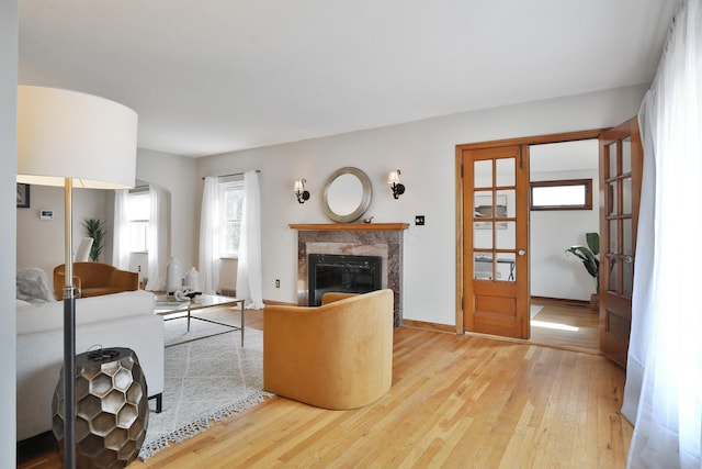 unfurnished living room with wood-type flooring, baseboards, and a high end fireplace