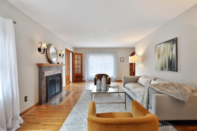 living room featuring light wood-type flooring, a fireplace, and baseboards