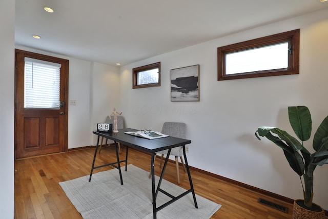 office area featuring light wood-type flooring, plenty of natural light, visible vents, and baseboards