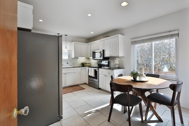 kitchen with appliances with stainless steel finishes, dark countertops, white cabinets, and backsplash