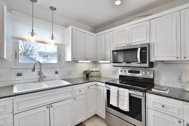 kitchen featuring a sink, white cabinets, appliances with stainless steel finishes, decorative backsplash, and pendant lighting