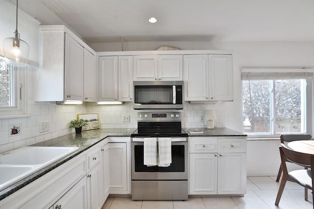 kitchen with appliances with stainless steel finishes, light tile patterned flooring, backsplash, and white cabinets