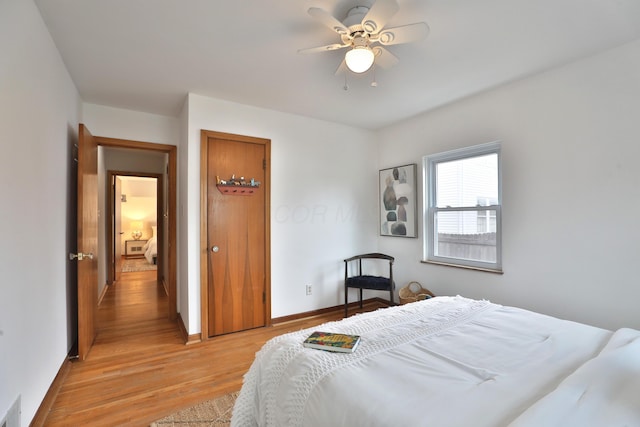 bedroom with a ceiling fan, light wood-type flooring, visible vents, and baseboards