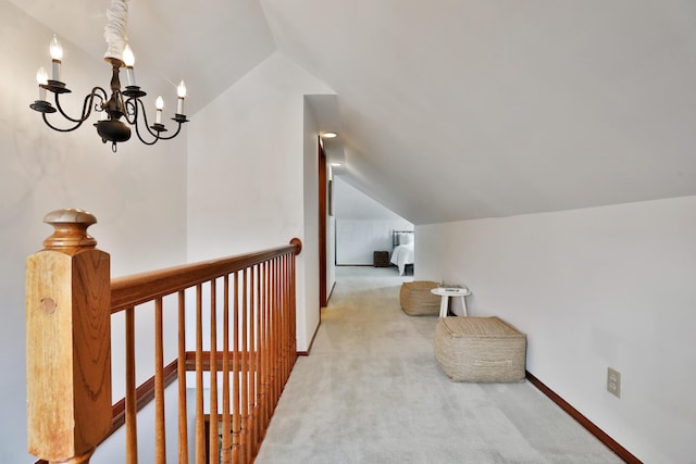 interior space with a chandelier, carpet floors, an upstairs landing, baseboards, and vaulted ceiling