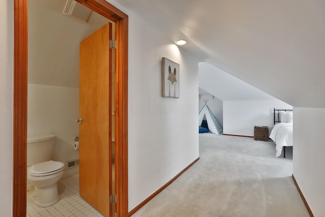 hall featuring carpet floors, visible vents, vaulted ceiling, and baseboards