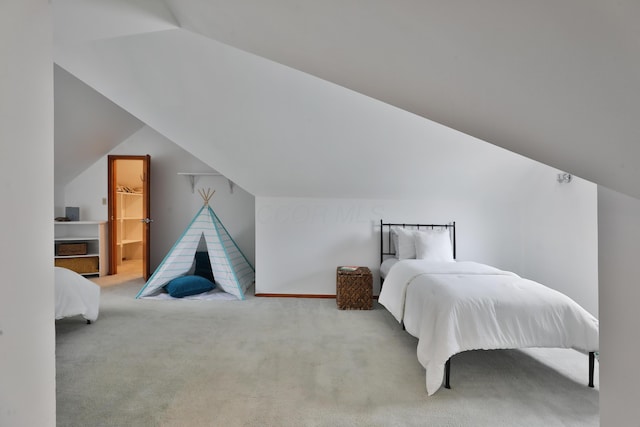 carpeted bedroom with vaulted ceiling and a spacious closet