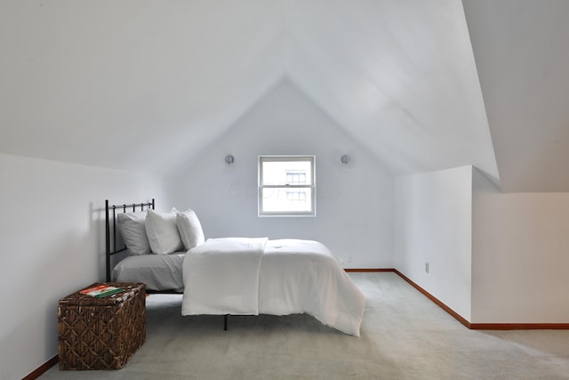 bedroom featuring light carpet, vaulted ceiling, and baseboards