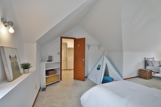 carpeted bedroom featuring lofted ceiling, baseboards, and a walk in closet