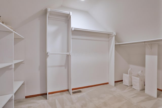 walk in closet with carpet, visible vents, and lofted ceiling