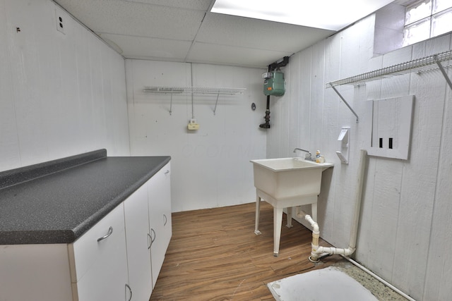 clothes washing area with wood walls and wood finished floors