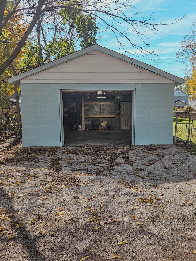 detached garage featuring aphalt driveway and fence